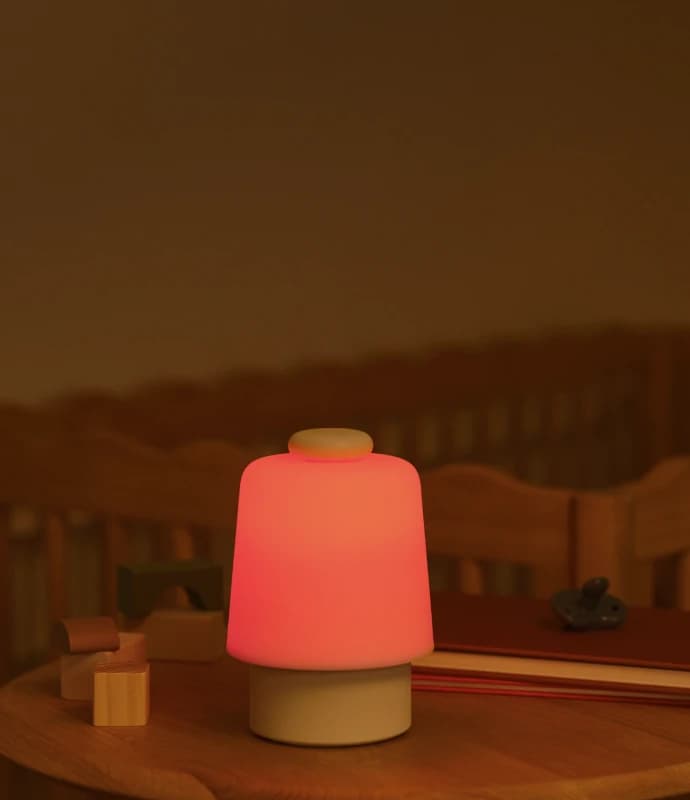 Lit up Hatch Baby on a nursery table next to some baby toys