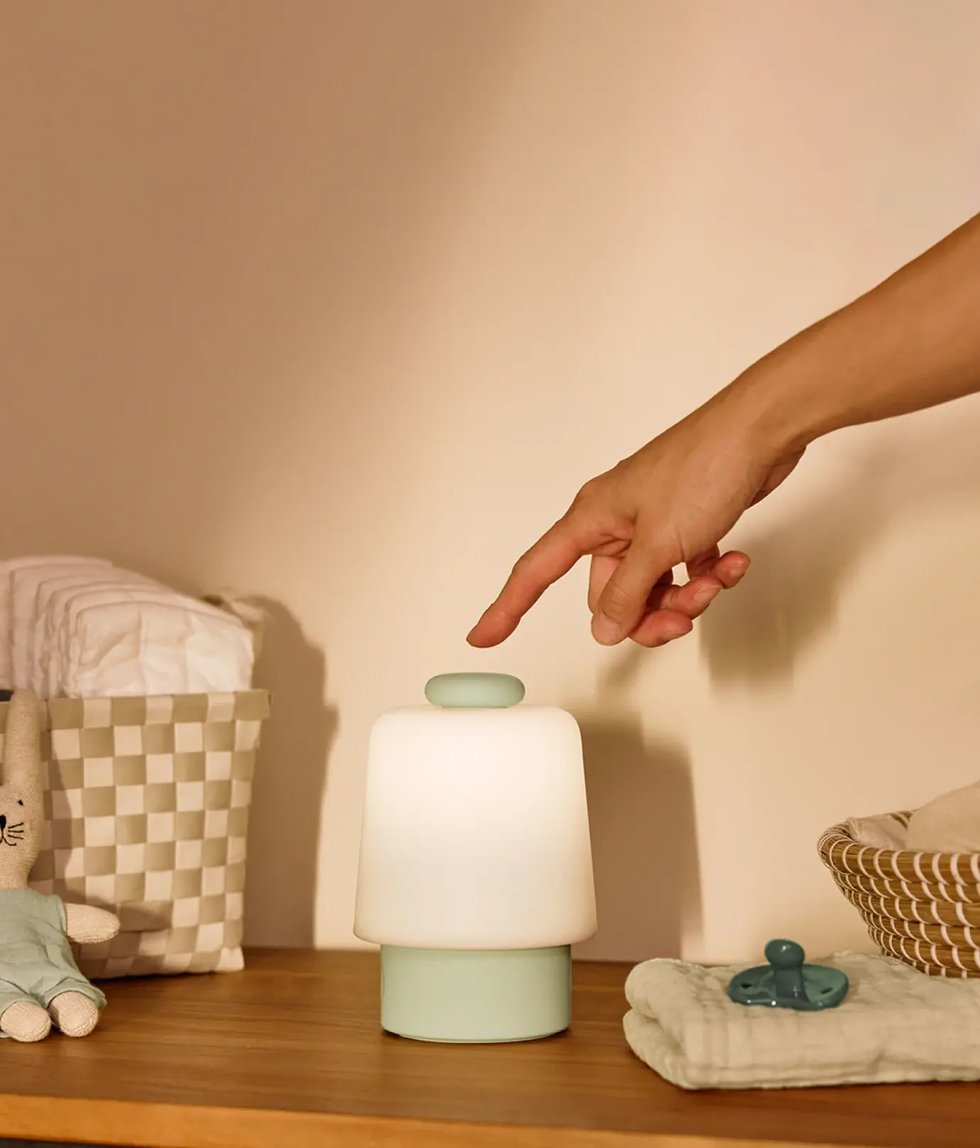 Hand touching the top button on a mint colorway Hatch baby on a changing station