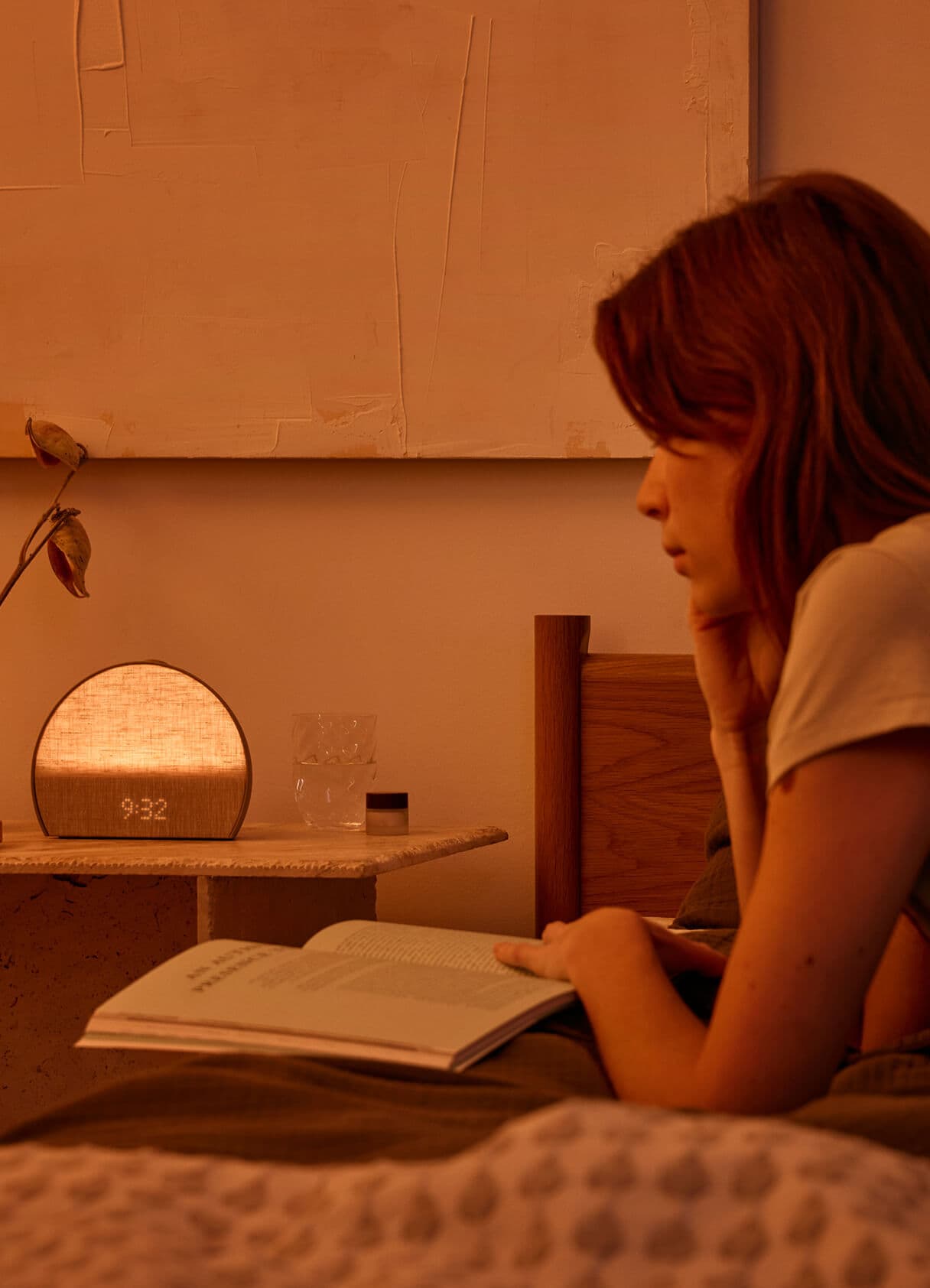 Woman reading book with Restore illuminated on nightstand